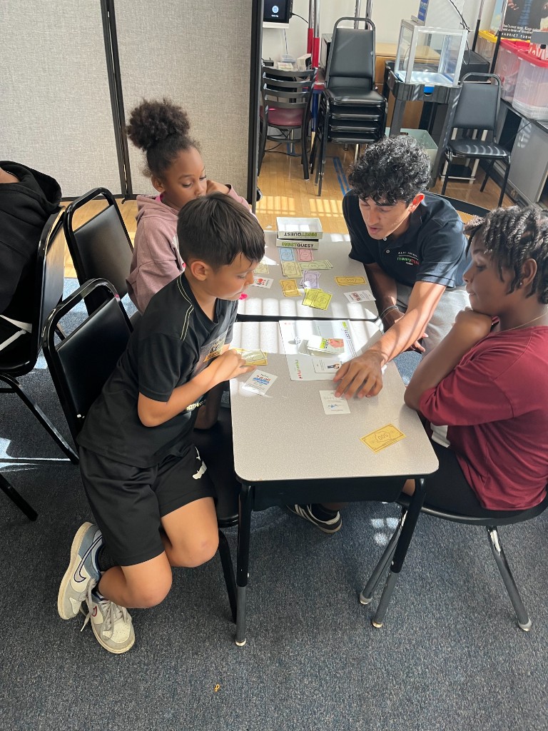 A facilitator coaching a small group of students through InvestQuest
