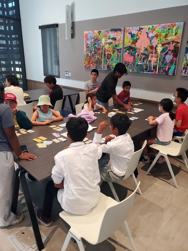 A facilitator helping kids play InvestQuest in a library