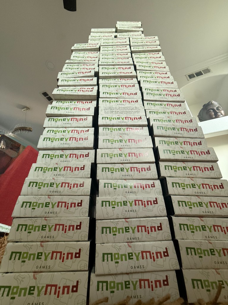 A tall stack of MoneyMind Games boxes ready for programs