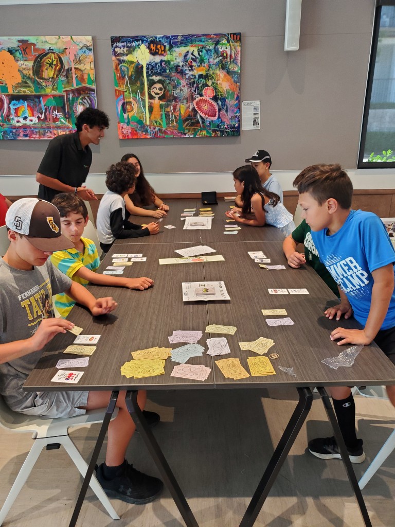 Kids playing InvestQuest around a library table