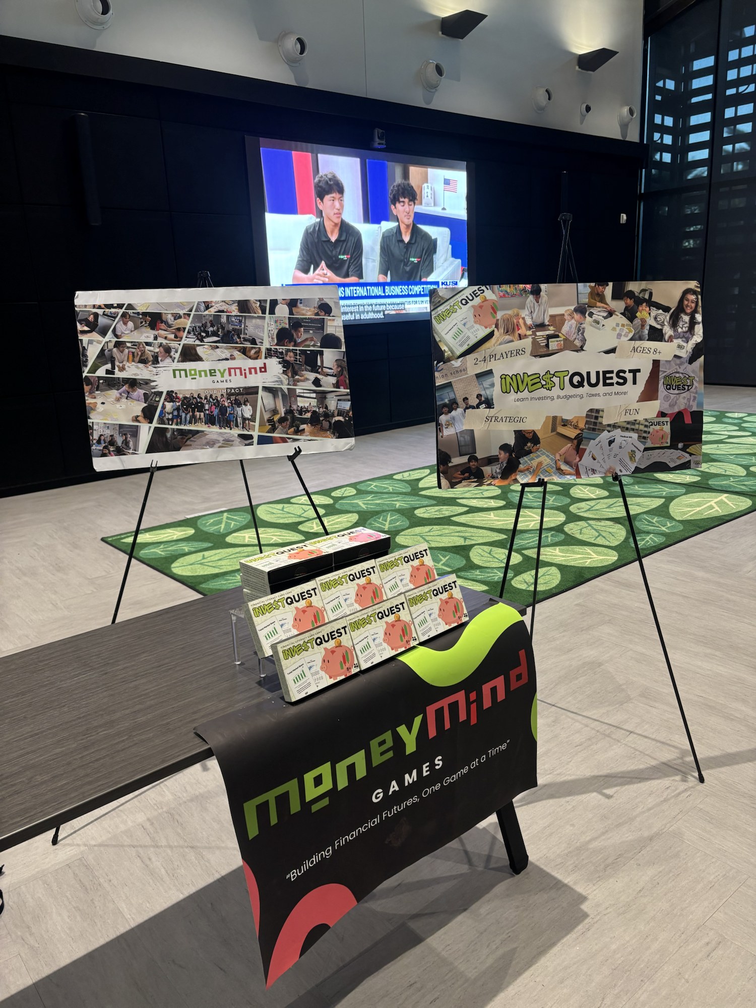 MoneyMind Games booth with InvestQuest boxes and impact posters