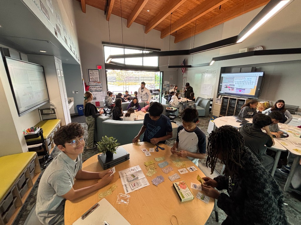 Students playing InvestQuest together around classroom tables